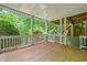 Covered back porch with wooden deck and white railings, overlooking lush greenery and steps at 420 Big Bend Trl, Sugar Hill, GA 30518