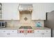 Close-up of a kitchen featuring stainless steel range hood and gas cooktop at 420 Big Bend Trl, Sugar Hill, GA 30518