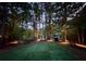 Night scene with outdoor lighting illuminating a private backyard with views of the lake at 4531 Kings Lake Dr, Marietta, GA 30067