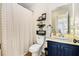 Cozy bathroom with a shower-tub, stylish shower curtain, and decorative shelves above the toilet and black hardware at 7760 Poppy Dr, Winston, GA 30187