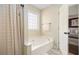 Bright bathroom featuring a soaking tub with tile surround and a view into the primary bedroom at 7760 Poppy Dr, Winston, GA 30187