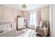 Bedroom featuring a crib, comfortable chair, and decoratively paneled pink walls at 7760 Poppy Dr, Winston, GA 30187