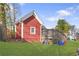 View of the backyard with lush green grass and a cozy red outbuilding with a wooden deck and steps leading down at 1081 Longley Nw Ave, Atlanta, GA 30318