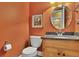 Bathroom featuring granite countertop, round mirror and orange colored walls at 249 Sycamore Pl, Decatur, GA 30030