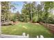 Spacious backyard featuring lush green lawn, playset, natural landscaping, and wooden fence at 304 Meadowbrook Ne Dr, Atlanta, GA 30342