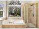 A luxurious soaking tub and shower with gold trim is located next to a large window with natural light at 825 Yosemite Dr, Suwanee, GA 30024