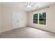 An empty bedroom with neutral walls and carpet. A window overlooks the fenced in backyard at 825 Yosemite Dr, Suwanee, GA 30024