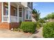 Brick-accented front porch with white railings, surrounded by lush greenery and manicured landscaping at 825 Yosemite Dr, Suwanee, GA 30024