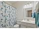 Bright bathroom featuring a floral shower curtain, white vanity, and a well-lit mirror at 11865 Brisbane Dr, Alpharetta, GA 30009