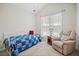Cozy bedroom with natural light, features a daybed with quilt and a comfy armchair for relaxing at 11865 Brisbane Dr, Alpharetta, GA 30009