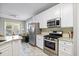 Well-equipped kitchen featuring stainless steel appliances, white cabinets, and a view of a cozy living space at 11865 Brisbane Dr, Alpharetta, GA 30009