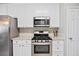 Kitchen features white cabinets, stainless steel appliances, granite counters, and tile backsplash at 11865 Brisbane Dr, Alpharetta, GA 30009