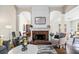 Cozy living room with brick fireplace, plush seating, and open archways to the dining and living spaces at 11865 Brisbane Dr, Alpharetta, GA 30009
