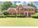 Charming brick home featuring a lush green lawn, manicured shrubs, and classic black shutters, offering curb appeal at 395 Clubfield Dr, Roswell, GA 30075