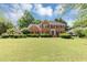 Beautiful brick home with a well-manicured lawn, dark shutters, and lovely landscaping offers classic curb appeal at 395 Clubfield Dr, Roswell, GA 30075