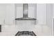 Close up of a modern kitchen featuring white cabinets, stainless steel vent hood and a white subway tile backsplash at 395 Clubfield Dr, Roswell, GA 30075