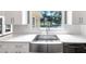 Bright kitchen features a stainless steel farmhouse sink, white cabinets, and a view to the backyard at 395 Clubfield Dr, Roswell, GA 30075