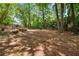 Spacious and partially shaded backyard surrounded by mature trees and a charming fence at 1061 Polo Club Nw Dr, Marietta, GA 30064
