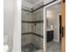 Modern bathroom boasts tiled shower with seamless glass door and dark pebble floor; barn door to vanity at 1061 Polo Club Nw Dr, Marietta, GA 30064