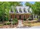 Charming brick home with lush landscaping, black door, and dormer windows at 1061 Polo Club Nw Dr, Marietta, GA 30064