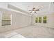 Bright main bedroom featuring carpeted floors, neutral walls, tray ceilings, and natural light from surrounding windows at 516 Winder Trl, Canton, GA 30114
