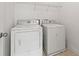 Practical laundry room featuring a standard washer and dryer set, plus overhead shelving at 325 Cranbrooke Cir, Suwanee, GA 30024