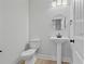Clean half-bathroom with pedestal sink, modern lighting, and neutral color scheme at 3877 Lake Sanctuary Way, Atlanta, GA 30349