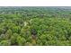 Aerial shot of a lush green forest with a glimpse of a home nestled among the trees and a long driveway at 5259 Sugar Ridge Dr, Sugar Hill, GA 30518