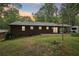 Rear view of a home with a patio, complemented by a lush green backyard and mature trees at 5259 Sugar Ridge Dr, Sugar Hill, GA 30518