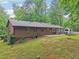 Backyard with a patio, green grass, and mature trees surrounding the property, and a partial view of the house at 5259 Sugar Ridge Dr, Sugar Hill, GA 30518