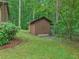 Backyard featuring a storage shed with brown siding, surrounded by green grass and trees at 5259 Sugar Ridge Dr, Sugar Hill, GA 30518
