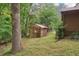 View of a backyard with a rustic storage shed and lush greenery, offering a private and tranquil outdoor space at 5259 Sugar Ridge Dr, Sugar Hill, GA 30518