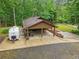 Carport, with a camper parked nearby, next to a home surrounded by trees at 5259 Sugar Ridge Dr, Sugar Hill, GA 30518
