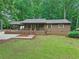Charming front view of a one-story home with a covered carport, well-kept lawn and mature trees at 5259 Sugar Ridge Dr, Sugar Hill, GA 30518