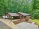 Aerial view of a single-story home with a covered carport, a well-manicured lawn, and a tranquil wooded backdrop at 5259 Sugar Ridge Dr, Sugar Hill, GA 30518