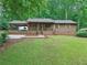 Charming single-story home with a covered porch, mature trees, and a well-maintained front lawn and wooden shutters at 5259 Sugar Ridge Dr, Sugar Hill, GA 30518