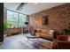 Modern living room with exposed brick wall, large window, leather sofa, and hardwood flooring at 800 Peachtree Ne St # 8429, Atlanta, GA 30308