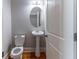 Charming powder room features a pedestal sink, oval mirror, and a white door at 204 Saintvry Path, Atlanta, GA 30349