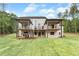 Backyard featuring a covered patio with steps leading to the lawn with mature trees surrounding the property at 2843 N North Bogan Rd, Buford, GA 30519