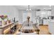 Open-concept dining area with modern table, chandelier, and seamless transition to a well-lit, white kitchen at 3819 Shane Ct, Ellenwood, GA 30294