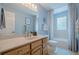 Well-lit bathroom with a vanity, decorative mirror, and tub/shower with patterned curtain at 435 Chantenay Pl, Alpharetta, GA 30022