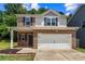 Charming two-story home featuring a brick facade, gray siding, and a two-car garage at 10786 Wheeler Trce, Hampton, GA 30228