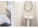 Elegant powder room with pedestal sink, oval mirror, and hardwood floors near the stairway at 196 Boulder Run, Hiram, GA 30141