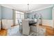 Dining room with blue walls, modern chandelier, wainscoting and a large window overlooking the backyard at 250 Chason Wood Way, Roswell, GA 30076