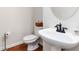 Half bathroom featuring wood floors, a toilet, and a stylish pedestal sink with bronze hardware at 1945 Bay Beauty Ln # 10, Austell, GA 30106