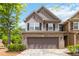 Charming two-story home featuring a brick facade and a two-car garage, set against a backdrop of lush greenery at 1945 Bay Beauty Ln # 10, Austell, GA 30106