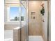 Modern shower with a glass door and a built-in niche for storage, enhanced by natural light from a window at 3248 Shirecrest Ln, Dacula, GA 30019