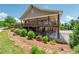 Exterior view of a clubhouse with a covered deck, stone supports and surrounded by trees, rock bed and shrubs at 2410 Bridle Bridge Trl, Cumming, GA 30040
