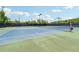 Well-maintained blue and green community tennis courts surrounded by fencing and tall, mature trees on a sunny day at 2410 Bridle Bridge Trl, Cumming, GA 30040