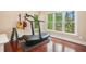 Bright home gym with a TreadRunner, free weights, and hardwood floors overlooking a beautiful wooded landscape at 300 Wesfork Nw Way, Suwanee, GA 30024